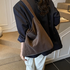Deep brown minimalist tote bag in matte suede leather worn over the shoulder