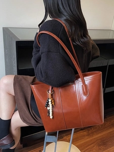 Grande borsa tote marrone con nappina di perline decorativa su modella per il pendolarismo quotidiano
