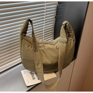 Detail of olive green puffy nylon shoulder bag showing adjustable strap with silver buckle