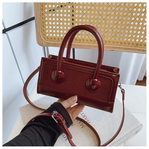 Detail of a vintage dark red mini handbag in glossy finish with adjustable strap and handles