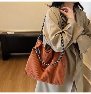 Close-up of burnt orange corduroy tote bag featuring woven rope shoulder strap detail