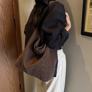 Detail view of large dark brown leather tote bag showing soft texture and shoulder strap