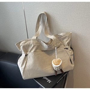 Détail d'un sac cabas en nylon blanc cassé avec un charm en peluche et un cordon