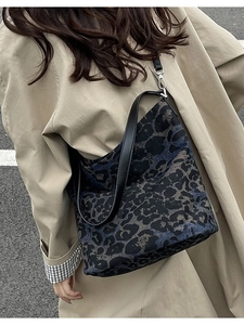 Leopard print canvas tote bag with black leather straps worn by model in city setting