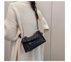 Detailed view of black checkered pillow bag with silver buckle and studs on white sweater