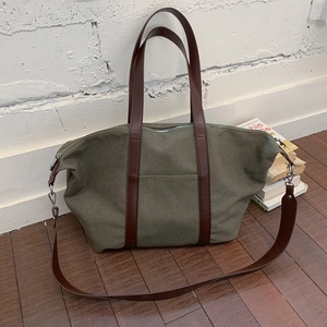Vue détaillée du sac en toile vert olive avec poignées en cuir marron et boucles argent