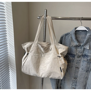 Détail du sac fourre-tout en nylon beige avec cordon de serrage et étiquette