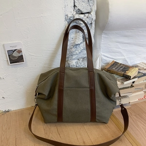 Détail du sac fourre-tout en toile olive avec poignées en cuir marron et bandoulière