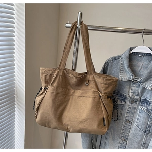 Détail du grand sac cabas kaki avec cordons de serrage latéraux et poche avant
