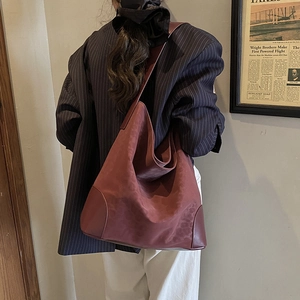 Detail of burgundy tote bag with reinforced bottom stitching and soft leather texture