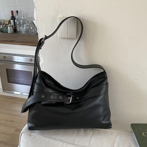 Close-up of black PU leather shoulder bag with decorative metal buckle belt and soft texture