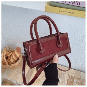 Detail of dark burgundy tote with matte suede and glossy leather texture contrast