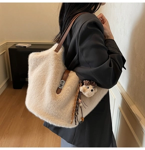 Gros plan sur le sac seau beige en peluche avec lanières en cuir et charme d'ours