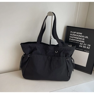 Détail d'un sac cabas en nylon noir avec cordons de serrage réglables et zip métallique