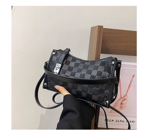 Detail of checkered crossbody bag showing metallic twist lock and silver rivet accents