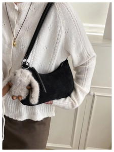 Detail of vintage black suede hobo bag with a cute plush rabbit pendant charm accessory