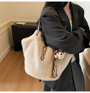 Détail du sac seau en fausse fourrure beige avec bandoulière en cuir et breloque ours