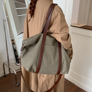 Détail du sac fourre-tout en toile vert armée avec poignées en cuir et grande poche frontale