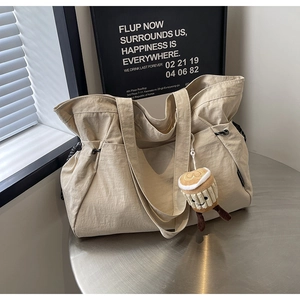 Détail du sac fourre-tout blanc cassé avec cordons latéraux et breloque en peluche café