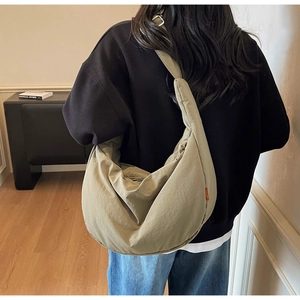 Khaki crescent canvas bag showing large capacity and wide strap on a model back
