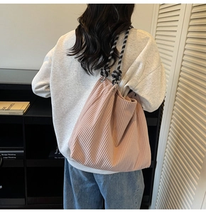 Close-up of pink corduroy tote bag featuring a black and white checkered rope shoulder strap