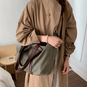 Vue détaillée du sac cabas en toile olive avec lanières en cuir marron en intérieur