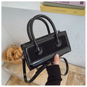 Detail of black textured contrast handbag featuring matte and glossy faux leather finish