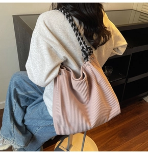 Detail of pink corduroy tote bag with black and white checkered strap shown on shoulder