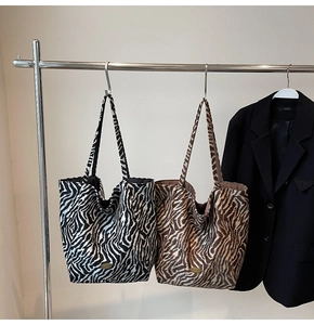 Detail showing zebra print tote bags in black and brown on a metal hanger