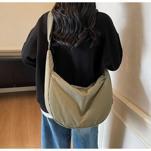 Khaki nylon crescent bag shown on model with adjustable strap and spacious interior