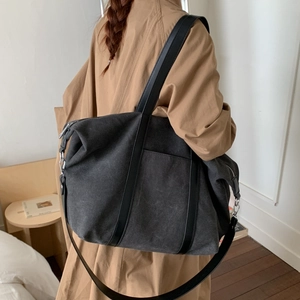 Modèle portant un grand sac cabas en toile gris foncé avec des lanières en cuir chic