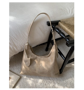 Minimalist tan suede half-moon tote bag with shoulder strap in a stylish home setting