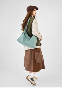 Light green canvas tote bag with wide strap styled in a vintage casual streetwear look