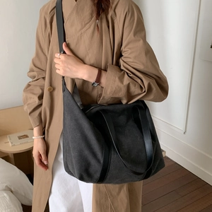 Détail d'un grand sac cabas noir en toile avec poignées en cuir et bandoulière réglable