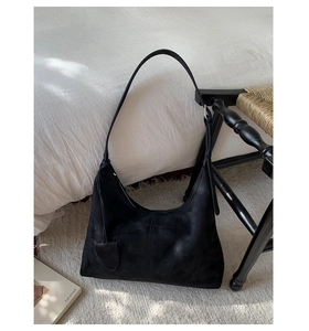 Detailed view of black matte minimalist tote bag with adjustable strap in a home setting