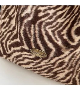 Close-up of zebra print tote bag featuring a vintage gold handmade metal emblem