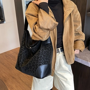 Detail of leopard print tote bag with black leather base and wide shoulder strap