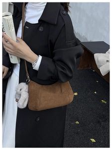 Detailaufnahme der braunen Wildledertasche mit Ziernaht und grauem Hasenanhänger