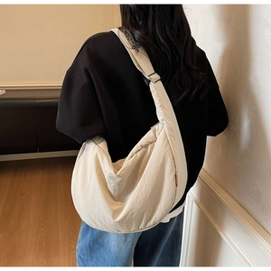 Detailed back view of a beige large capacity nylon crossbody bag worn by a model