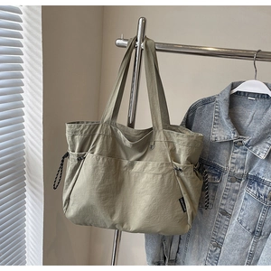 Détail d'un sac cabas en nylon avec grandes poches avant et cordons latéraux