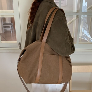 Détail d'un grand sac fourre-tout en toile marron foncé avec poignées contrastées et poche