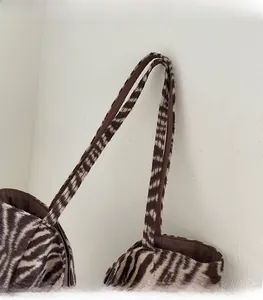 Detail of zebra pattern plush tote bag strap with soft faux fur texture and brown lining
