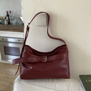 Detailed close-up of dark red vintage leather tote bag with silver metal belt buckle
