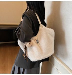 Détail du sac seau en fausse fourrure crème avec boucle en métal et breloque ours