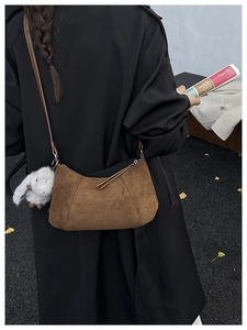 Braune Wildleder-Schultertasche mit Hasen-Anhänger an einem Model in herbstlicher Szene
