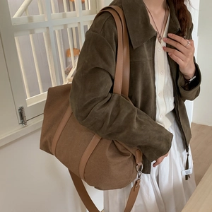 Sac cabas en toile marron foncé avec lanières en cuir porté par un mannequin asiatique