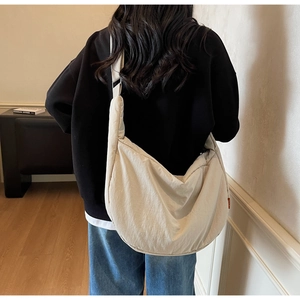 Back view of a large cream crescent canvas crossbody bag with wide adjustable shoulder strap
