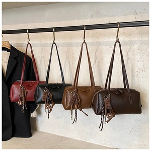 Detail view of four vintage oil wax leather shoulder bags in various colors with charms