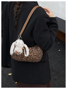 Detail der Zylindertasche mit Leopardenmuster, braunem Riemen und weißem Hasenanhänger