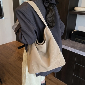 Detail view of large minimalist hobo bag in beige matte leather showing side reinforced patches